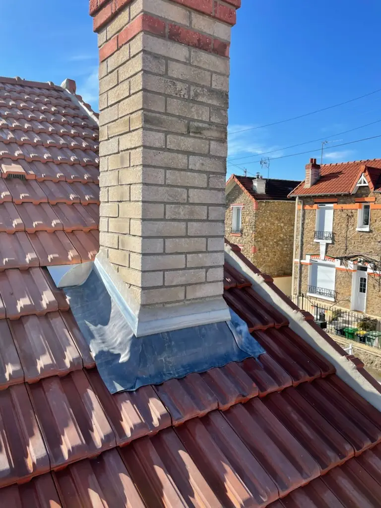 Réalisation d’un solin en zinc autour d’une cheminée sur toiture en tuiles, intervention de zinguerie pour assurer l’étanchéité en Île-de-France