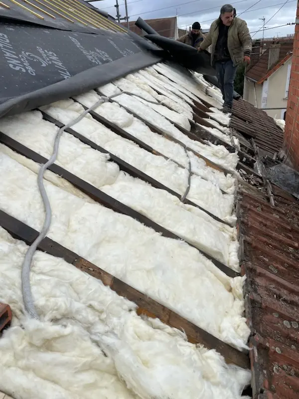 Travaux d’isolation de toiture avec pose d’isolant entre chevrons et écran sous-toiture lors d’un chantier de rénovation en Île-de-France
